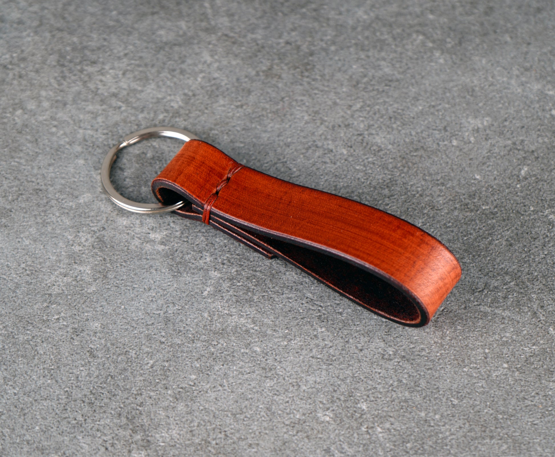 Brown leather keychain on a gray surface