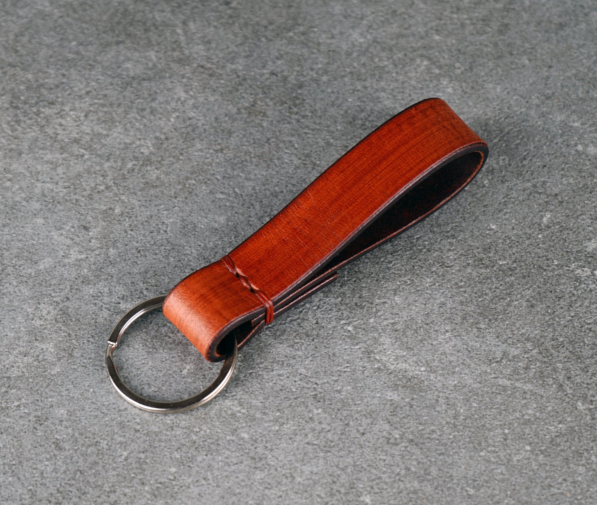 Brown leather keychain with a metal ring on a gray surface