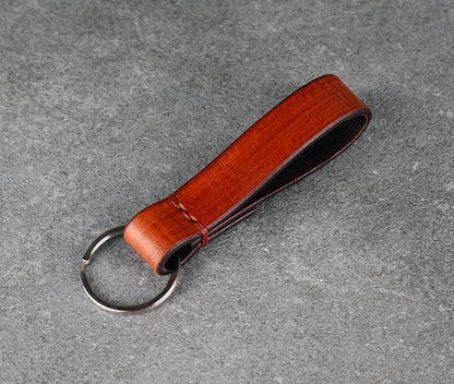 Brown leather keychain with a metal ring on a gray surface