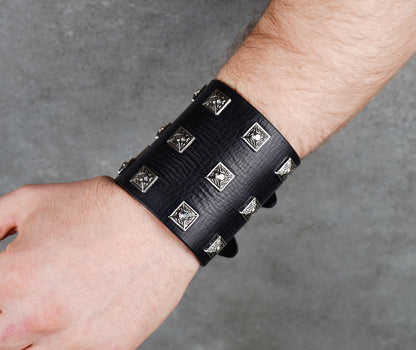 Black leather wristband with silver studs on a gray background