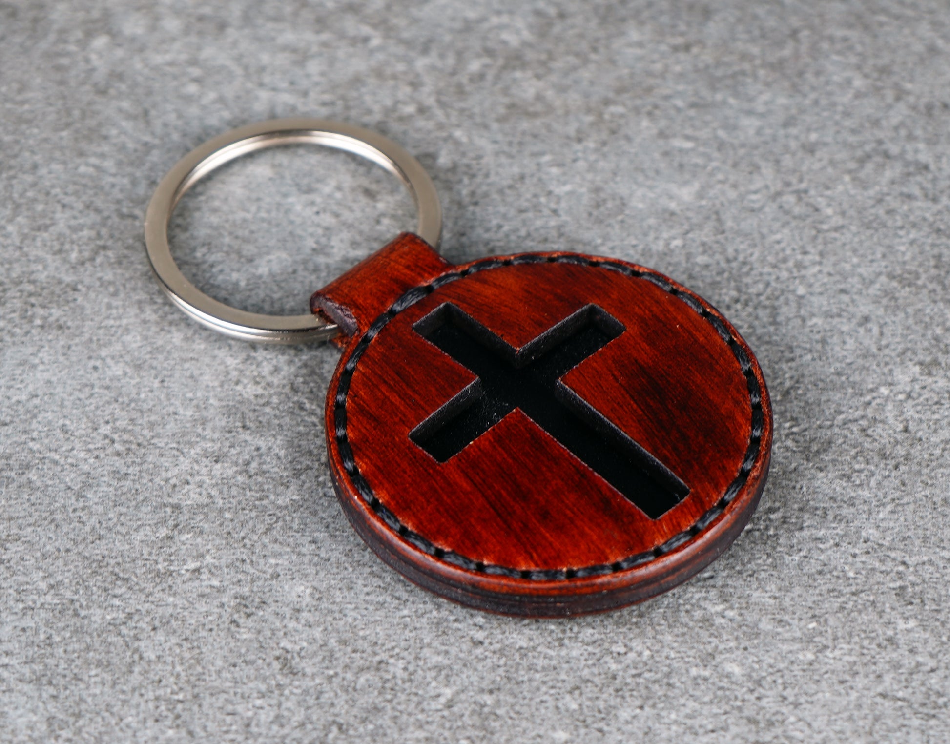 Brown leather keychain with black 'X' design on a gray surface
