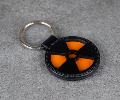 Keychain with a black and orange radiation symbol on a gray surface