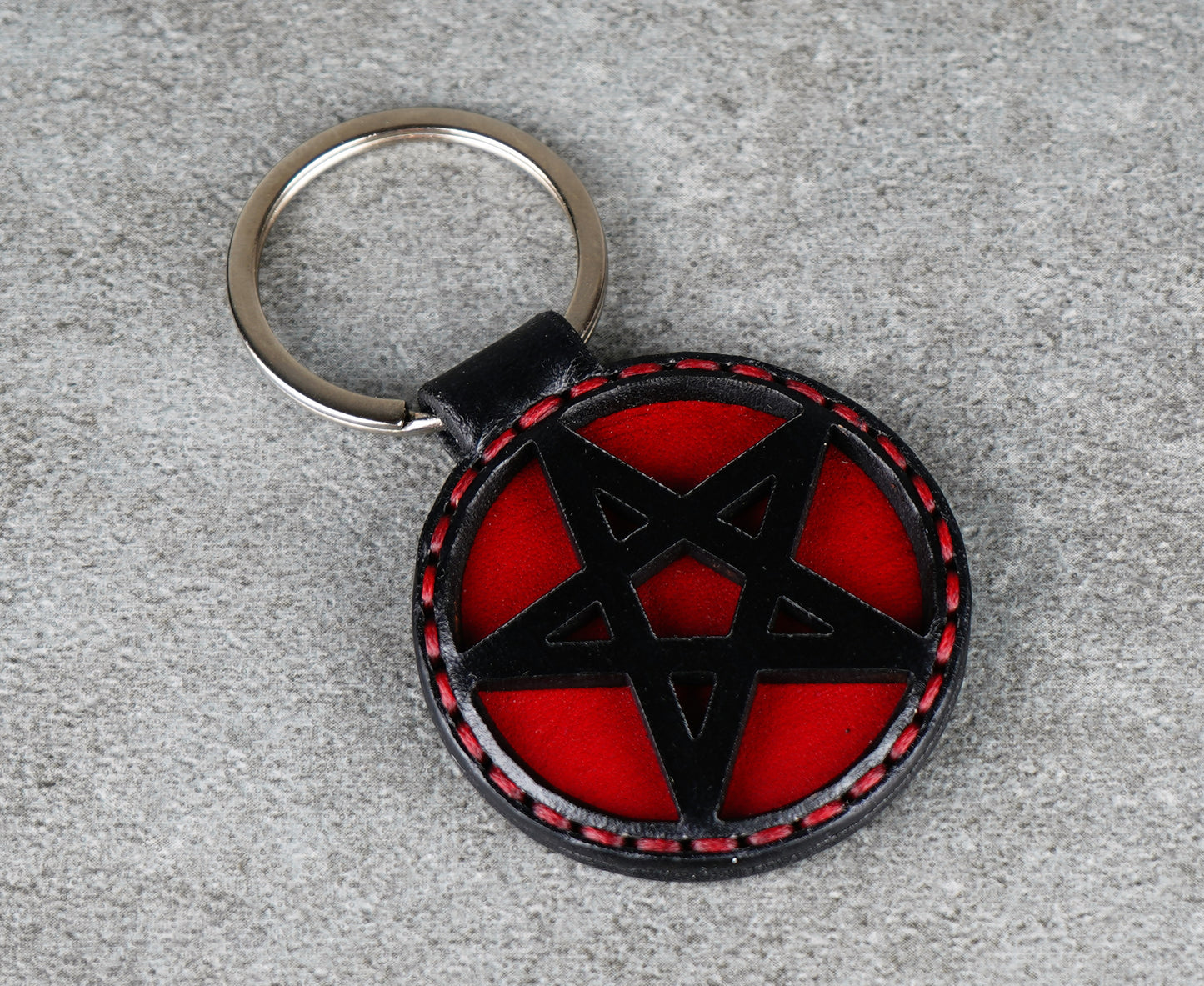 Keychain with red and black pentagram design on a gray surface