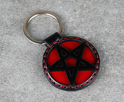 Keychain with red and black pentagram design on a gray surface