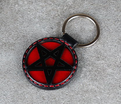 Keychain with black pentagram design on a red background, attached to a keyring.