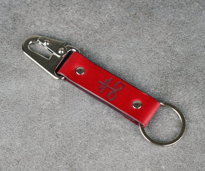 Red leather keychain with metal clip on a gray background