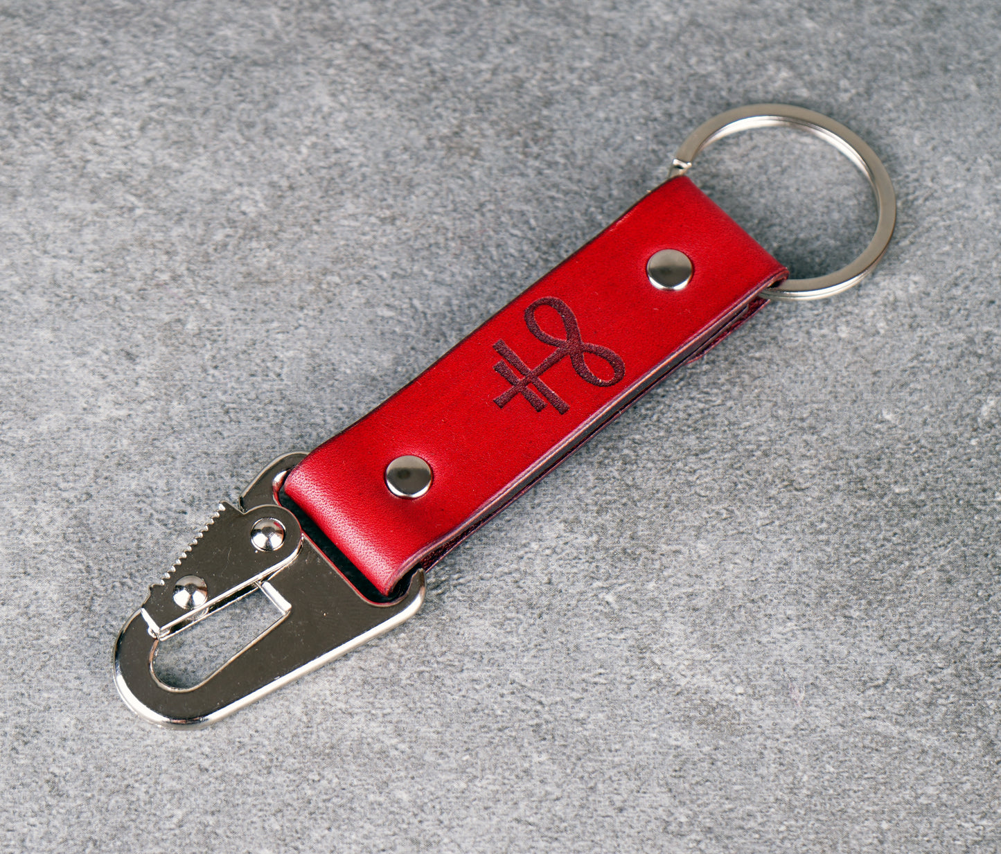 Red leather keychain with metal carabiner on a gray surface