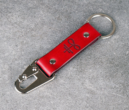 Red leather keychain with metal carabiner on a gray surface