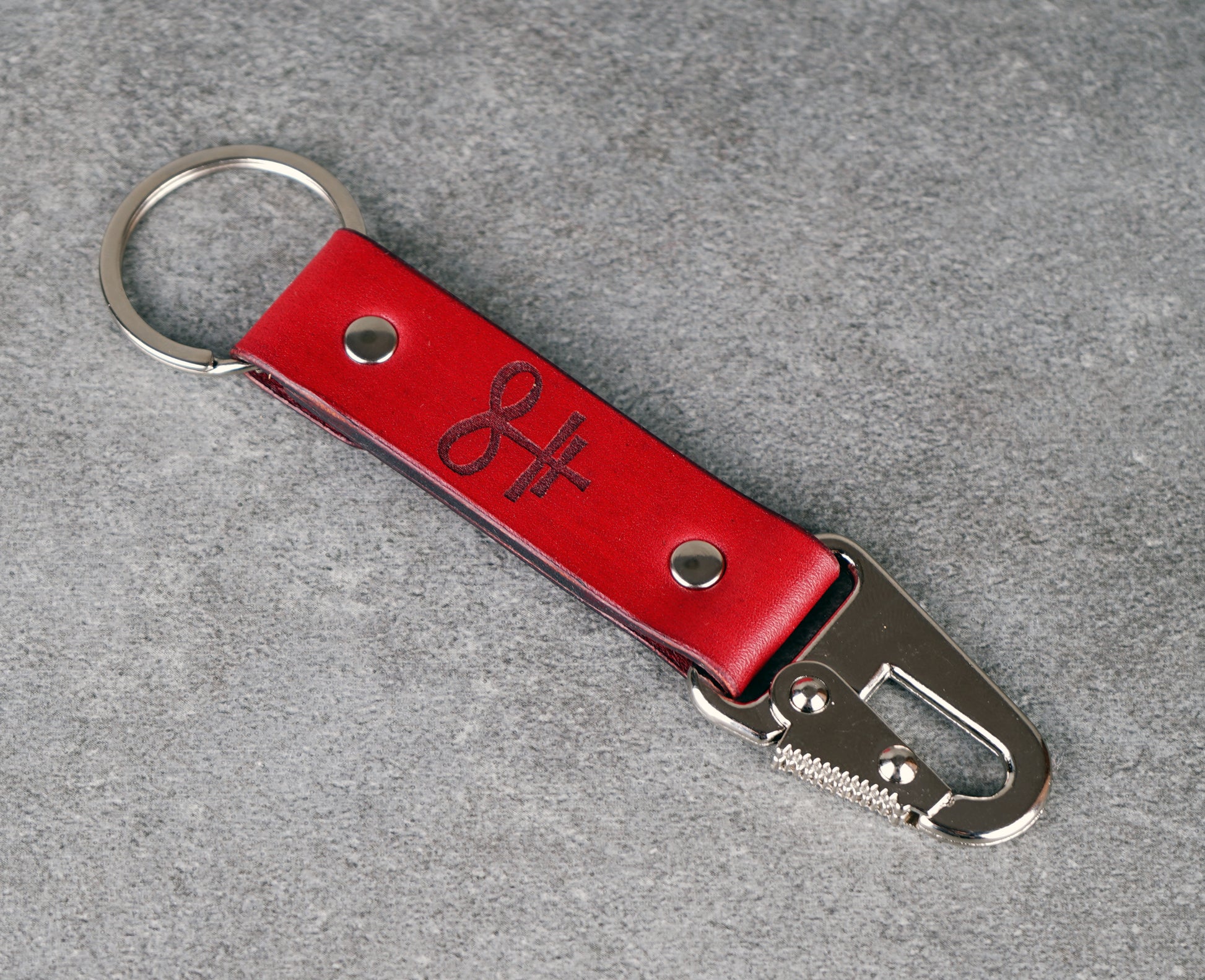 Red leather keychain with metal clip on a gray background