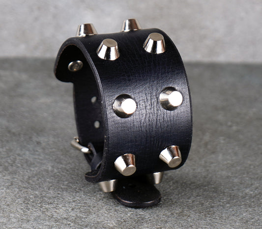 Black leather cuff with silver studs on a gray background