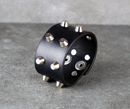 Black leather cuff with silver studs on a gray surface