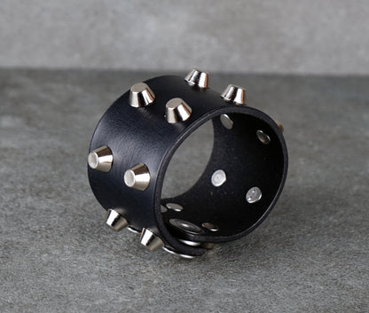 Black leather cuff with silver studs on a gray background