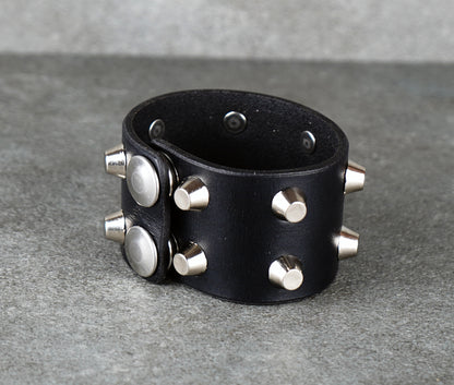 Black leather cuff with silver studs on a gray background