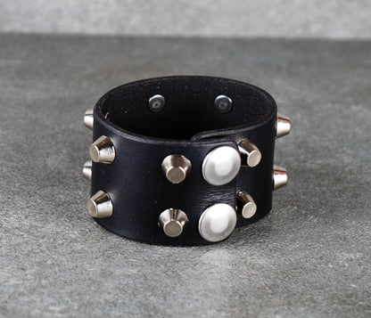 Black leather bracelet with silver studs on a gray surface