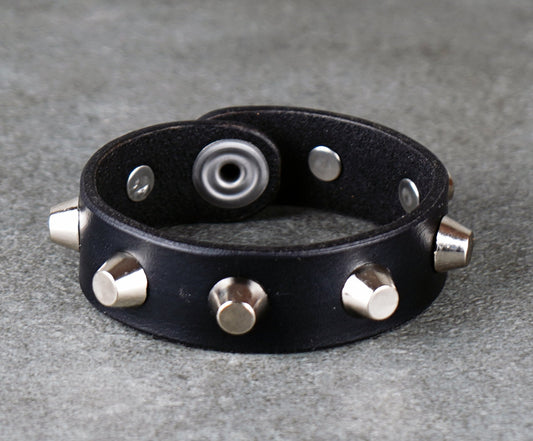 Black leather bracelet with metallic studs on a gray surface