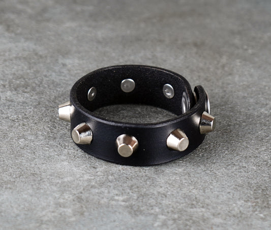 Black leather bracelet with metallic studs on a gray surface