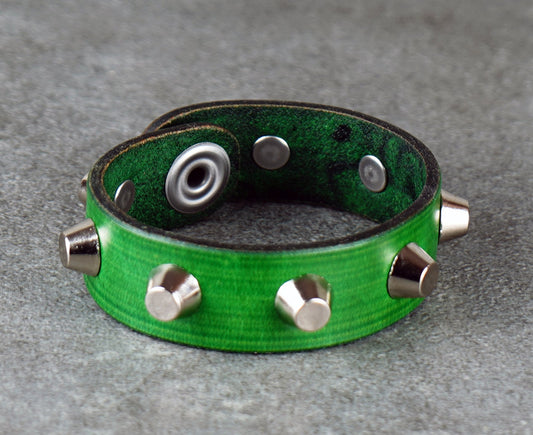 Green leather bracelet with metallic studs on a gray surface