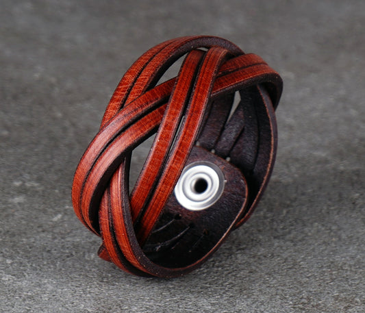 Brown leather bracelet with braided design on a gray surface