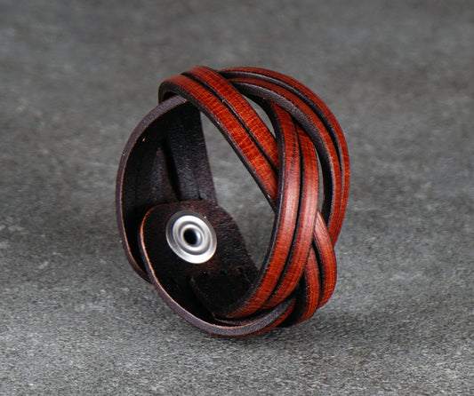 Brown leather bracelet with silver clasp on a gray surface