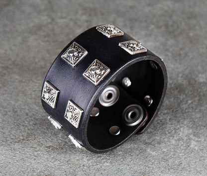 Black leather bracelet with silver metal studs on a gray surface