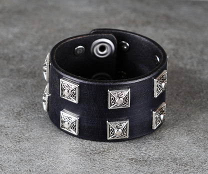 Black leather bracelet with silver studs on a gray surface