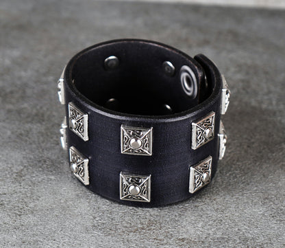 Black leather bracelet with silver studs on a gray surface