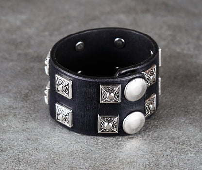 Black leather bracelet with silver studs on a gray surface