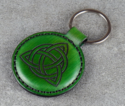 Green leather keychain with Celtic knot design on a gray surface