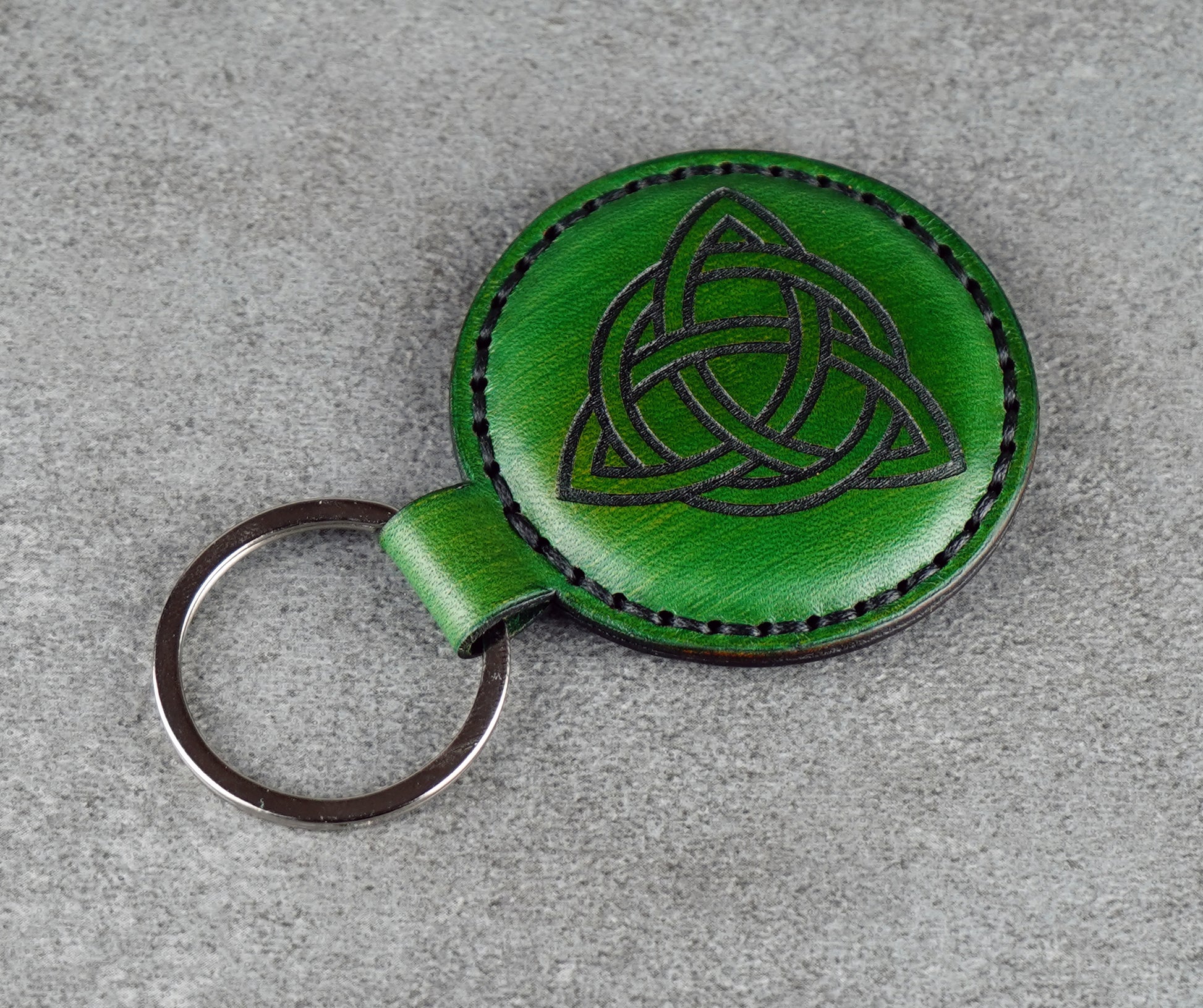 Green leather keychain with Celtic knot design on a gray surface