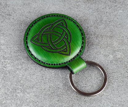 Green leather keychain with Celtic knot design on a gray surface