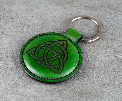Green leather keychain with Celtic knot design on a gray surface