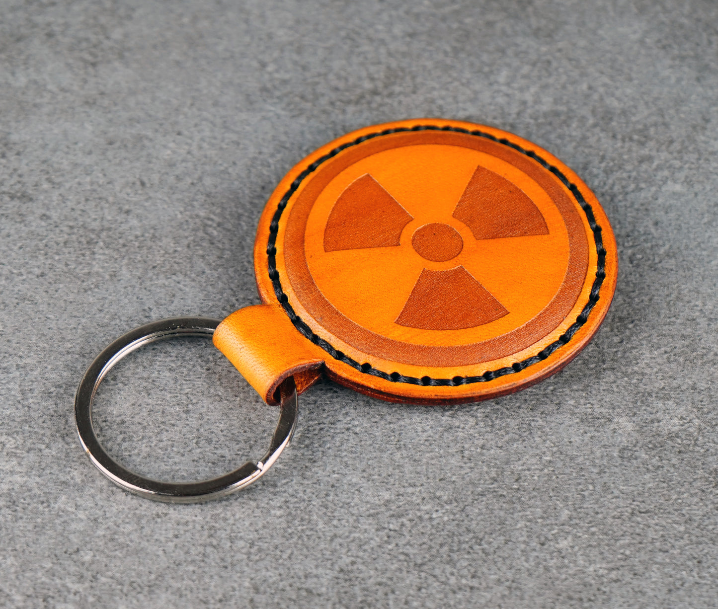 Yellow leather keychain with radiation symbol on a gray background