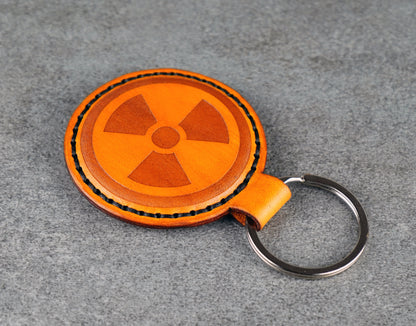 Round Yellow leather keychain with radiation symbol on a gray surface