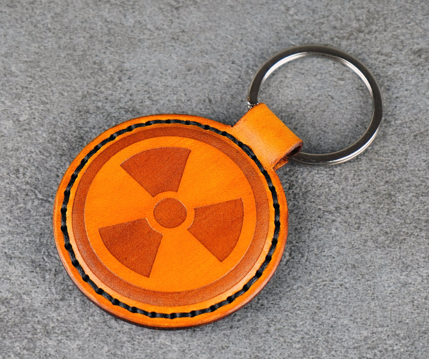 Yellow leather keychain with radiation symbol on a gray surface