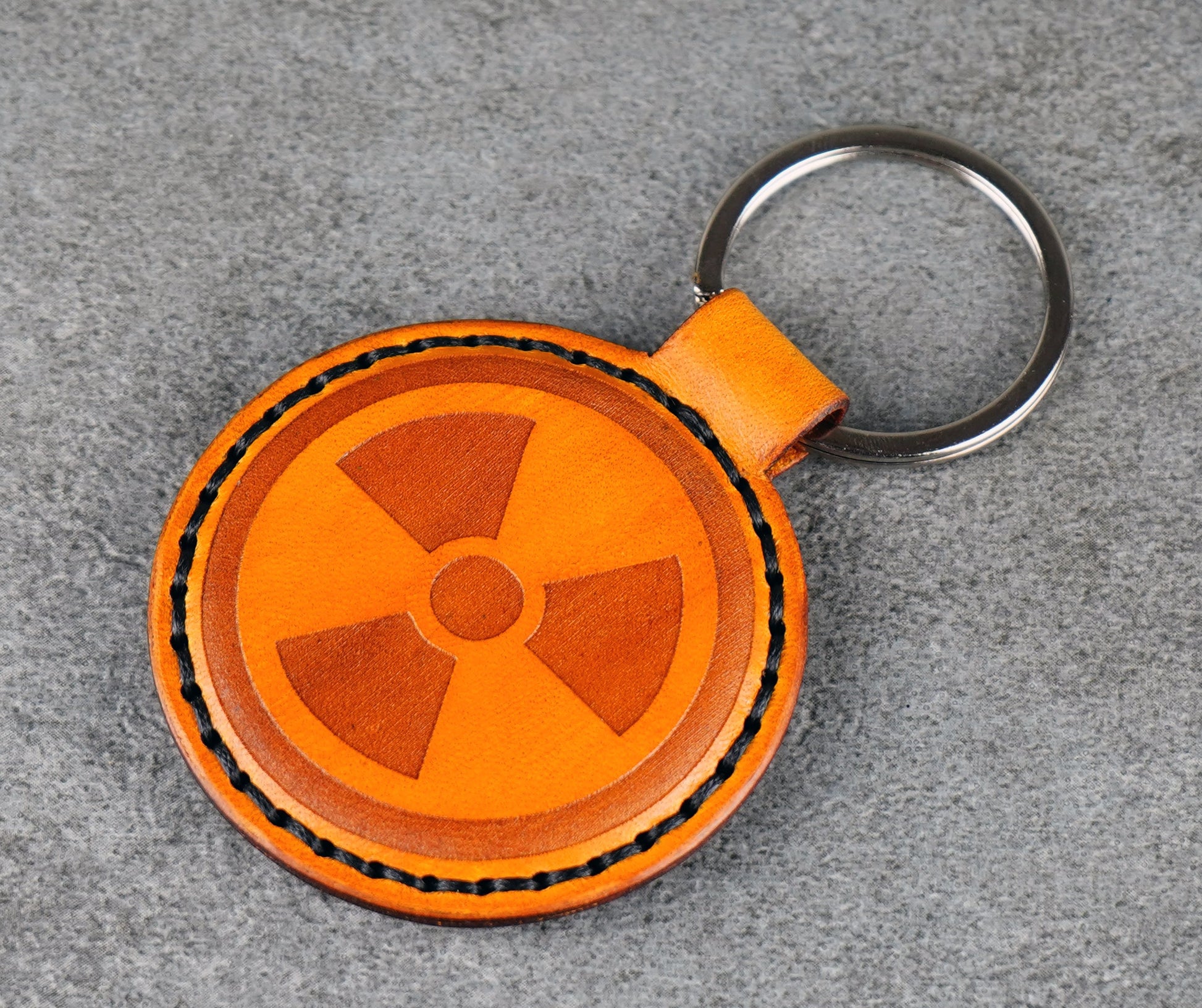Yellow leather keychain with radiation symbol on a gray surface