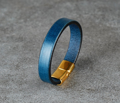 Blue leather bracelet with a gold clasp on a gray surface