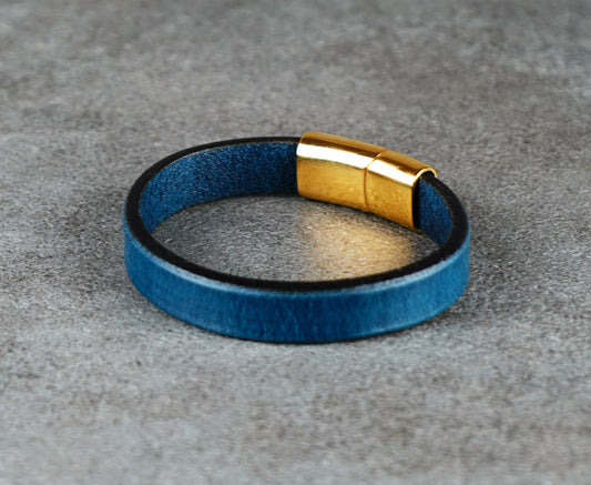 Blue leather bracelet with a gold clasp on a gray surface