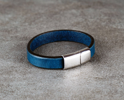 Blue leather bracelet with a silver clasp on a gray surface