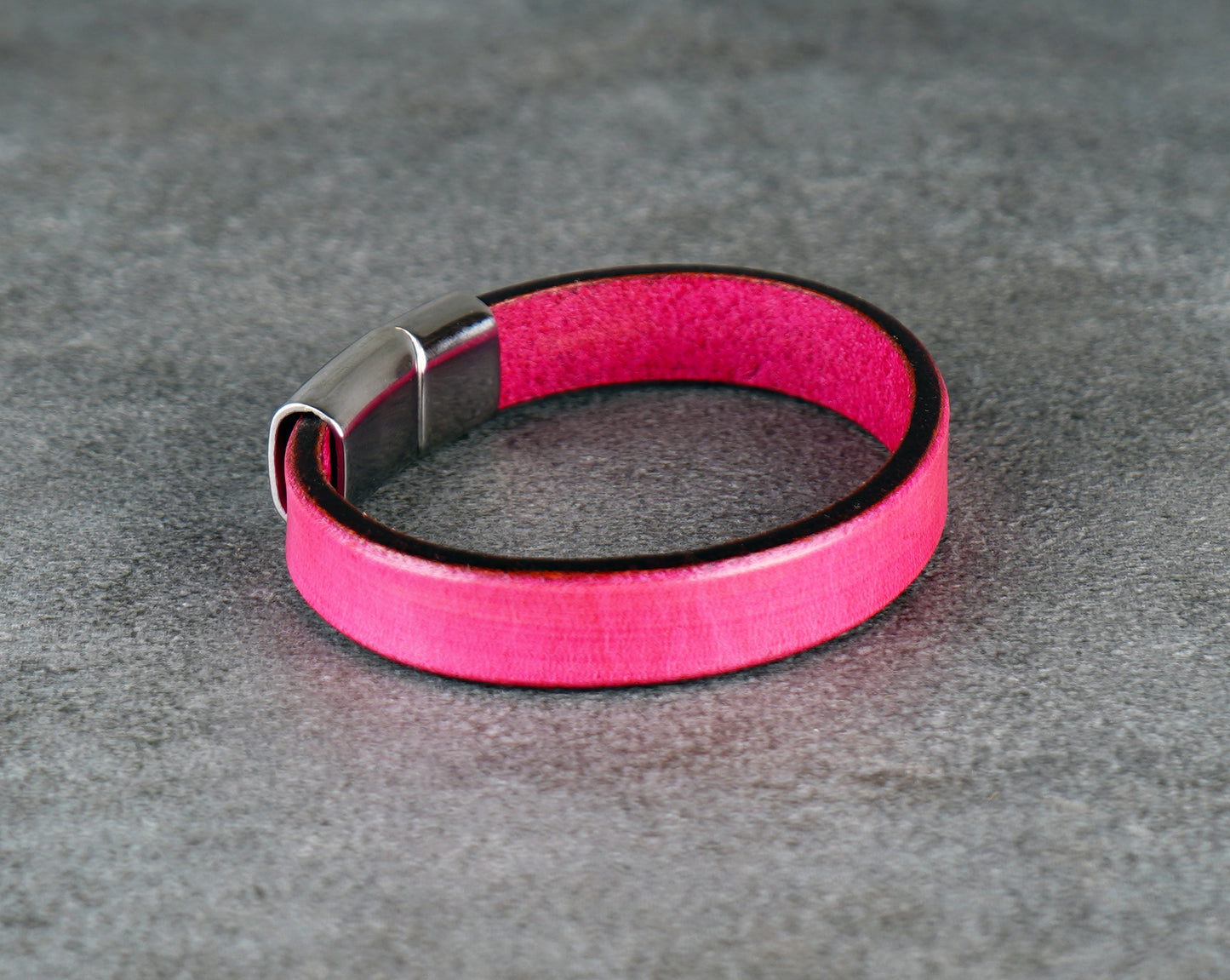 Pink bracelet a metallic buckle on a gray surface