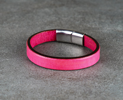 Pink leather bracelet with a silver clasp on a gray surface