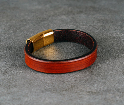 brown leather bracelet with gold clasp on a gray surface