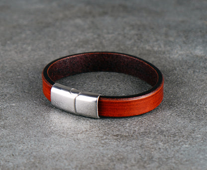Brown leather bracelet with a silver clasp on a gray surface