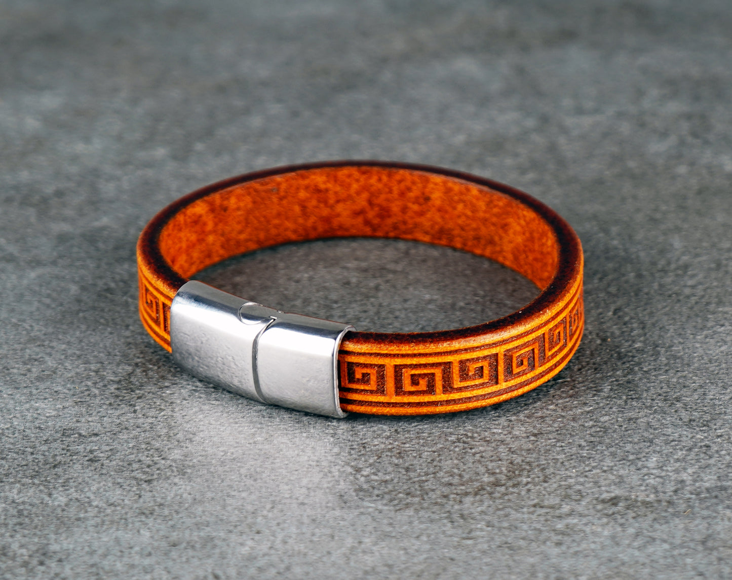 Yellow leather bracelet with a silver clasp on a gray surface