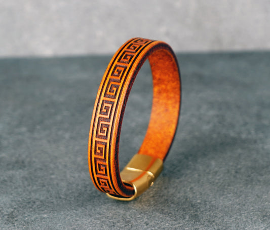 Yellow leather bracelet with gold accents on a gray surface