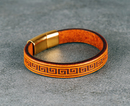 Yellow leather bracelet with gold clasp on a gray surface