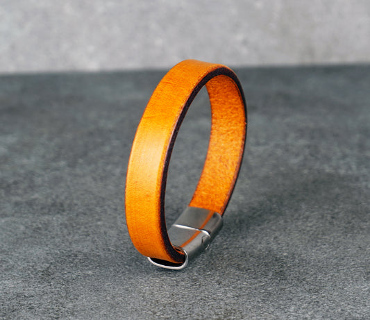 Yellow leather bracelet with a silver clasp on a gray surface