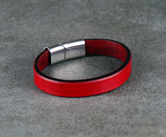 Red leather bracelet with a silver clasp on a gray surface