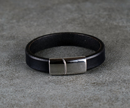Black leather bracelet with a silver clasp on a gray surface