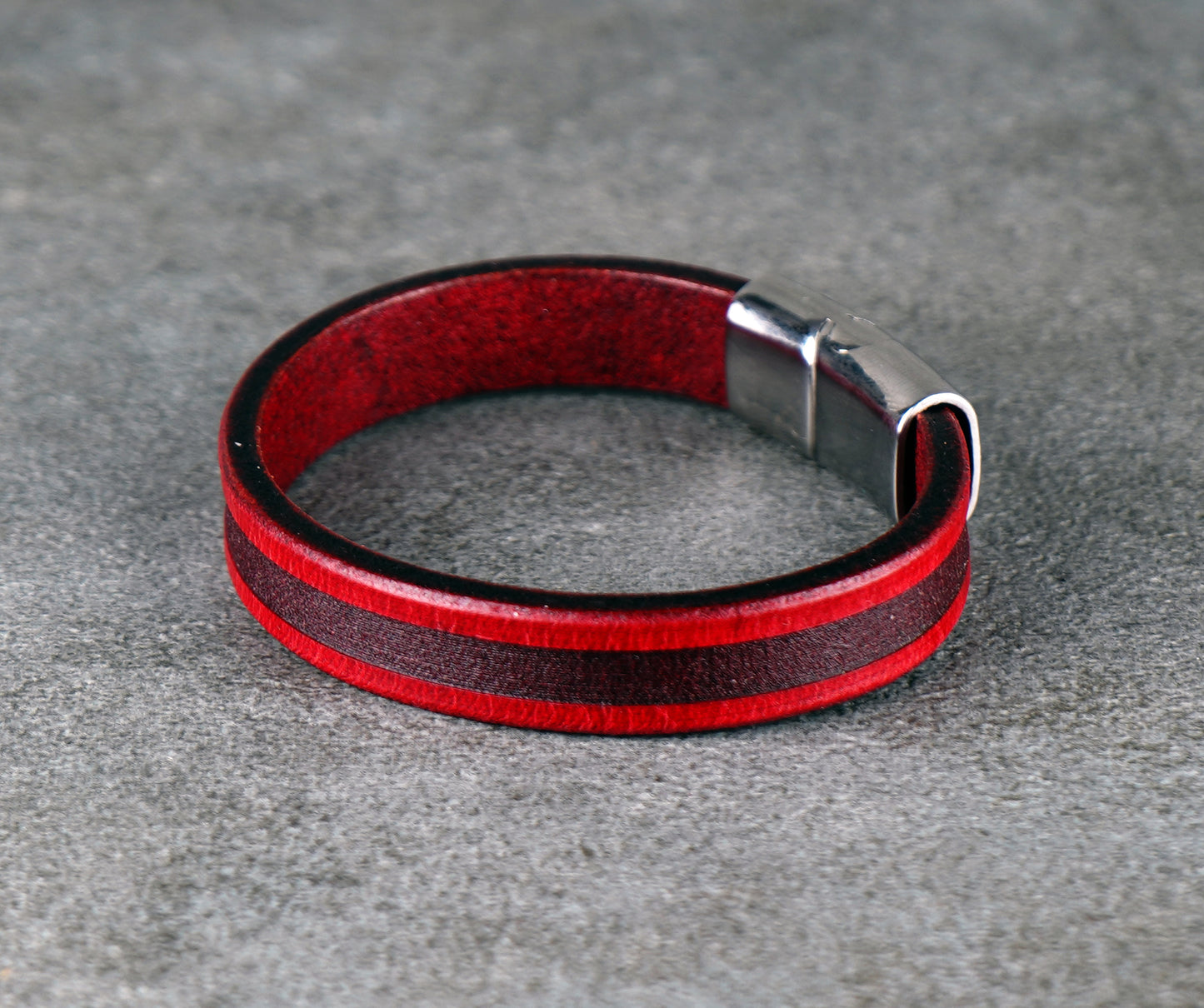 Red and black leather bracelet on a gray surface