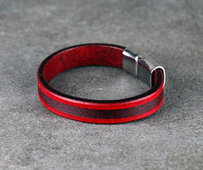 Red and black leather bracelet on a gray surface